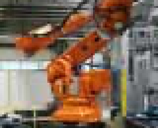 Ein großer orangener Roboterarm wird in voller Größe in einer Produktionshalle dargestellt.