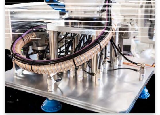 Ein dicker Kabelkanal, aus dem viele Kabel unterschiedlich abzweigen, ist auf einer silbernen Metallplatte befestigt.